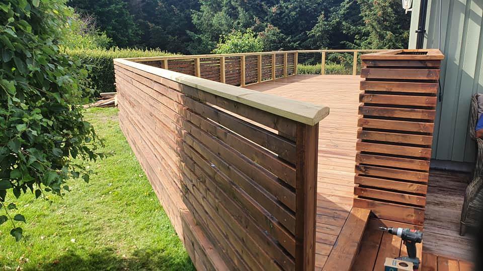 A long terrace with a tall slatted wooden rail along the garden