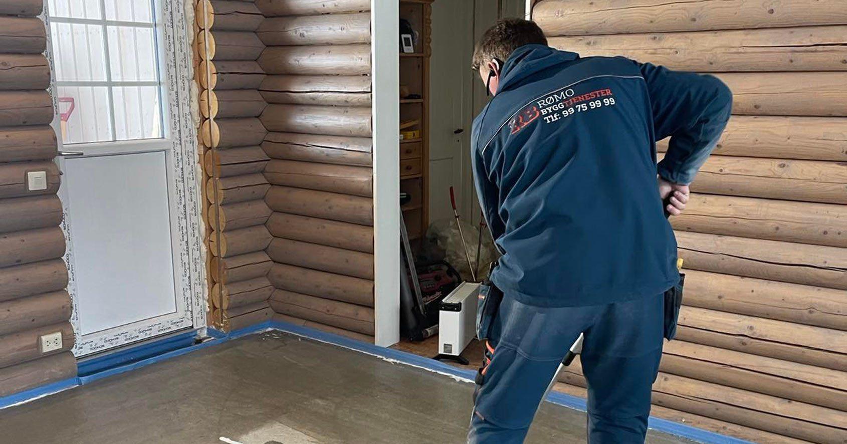 A Rømo carpenter fitting a door frame in a log-walled room