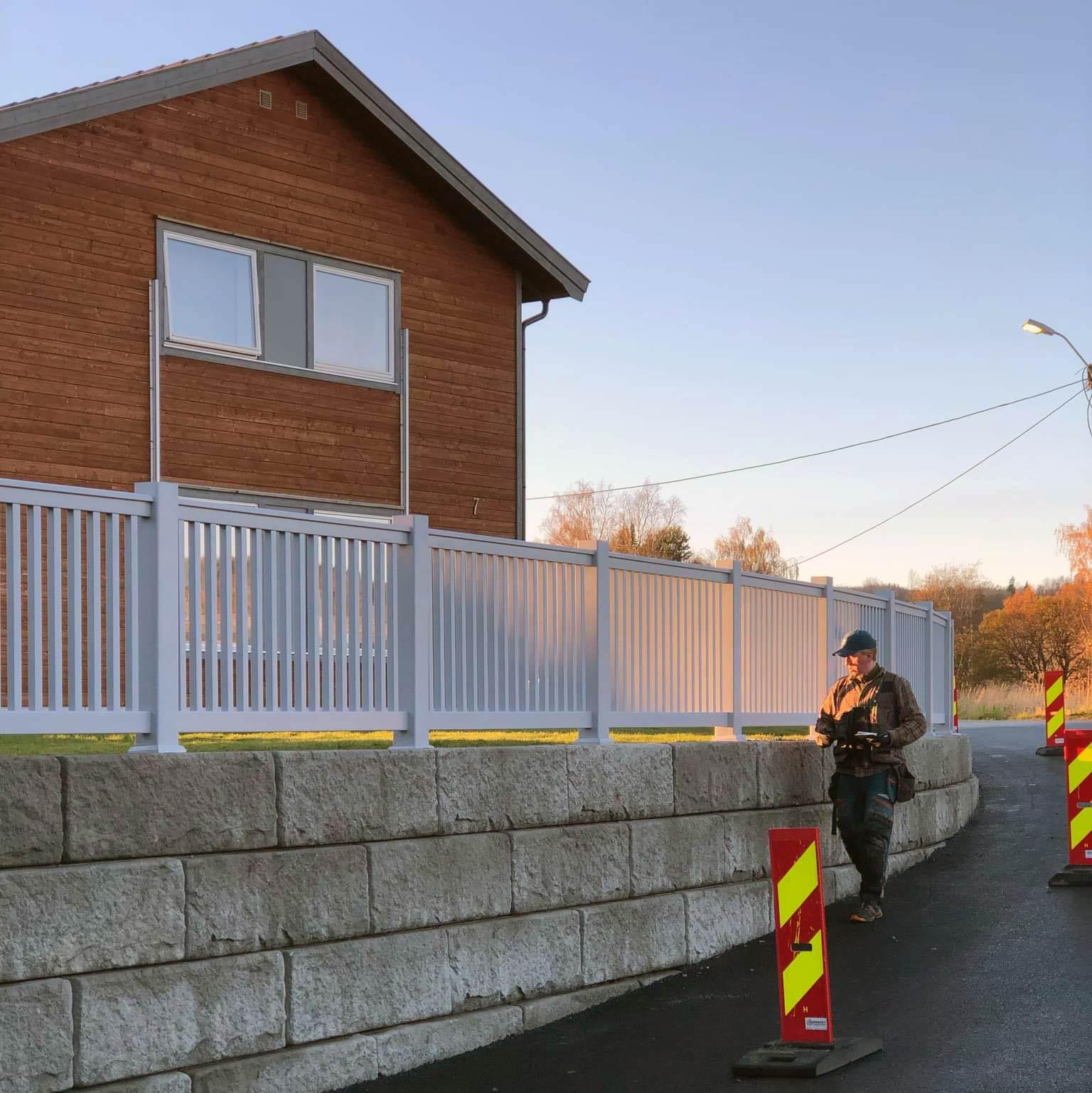 A white fence along a retaining wall in front of a house