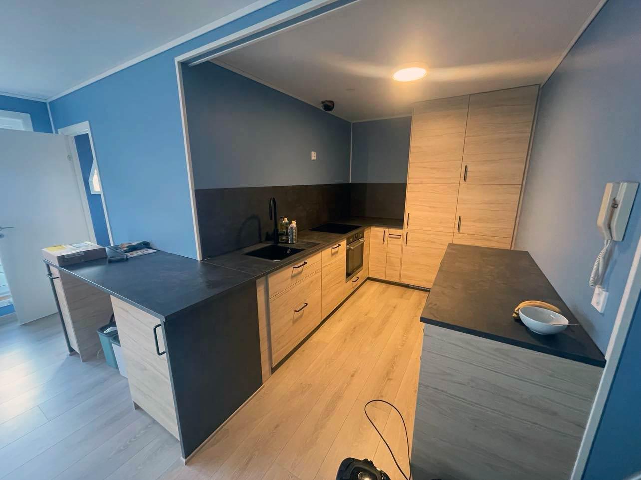 A new grey kitchen with a dark worktop and an island, wood floor