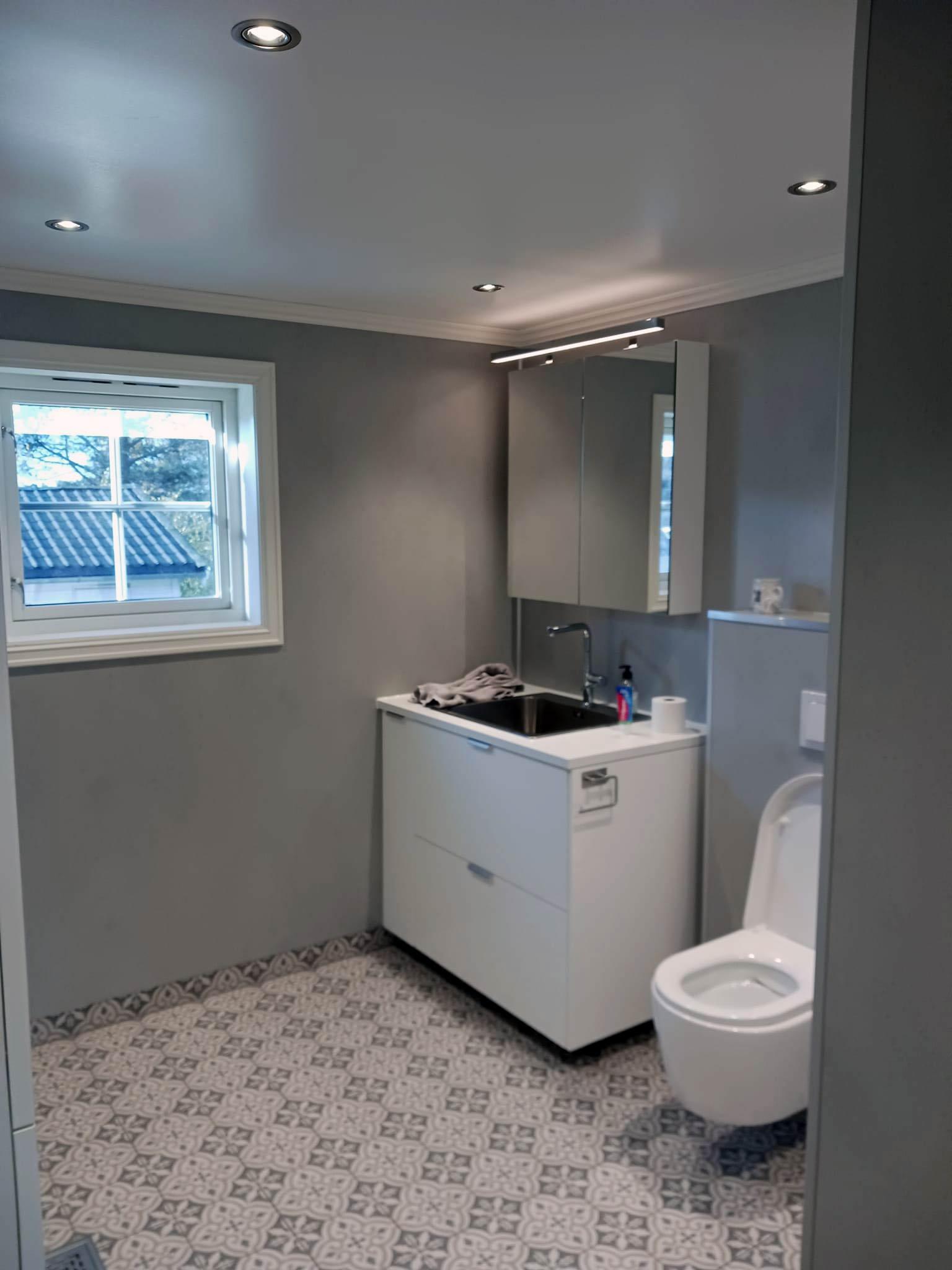 A small bathroom and laundry room with patterned floor tiles