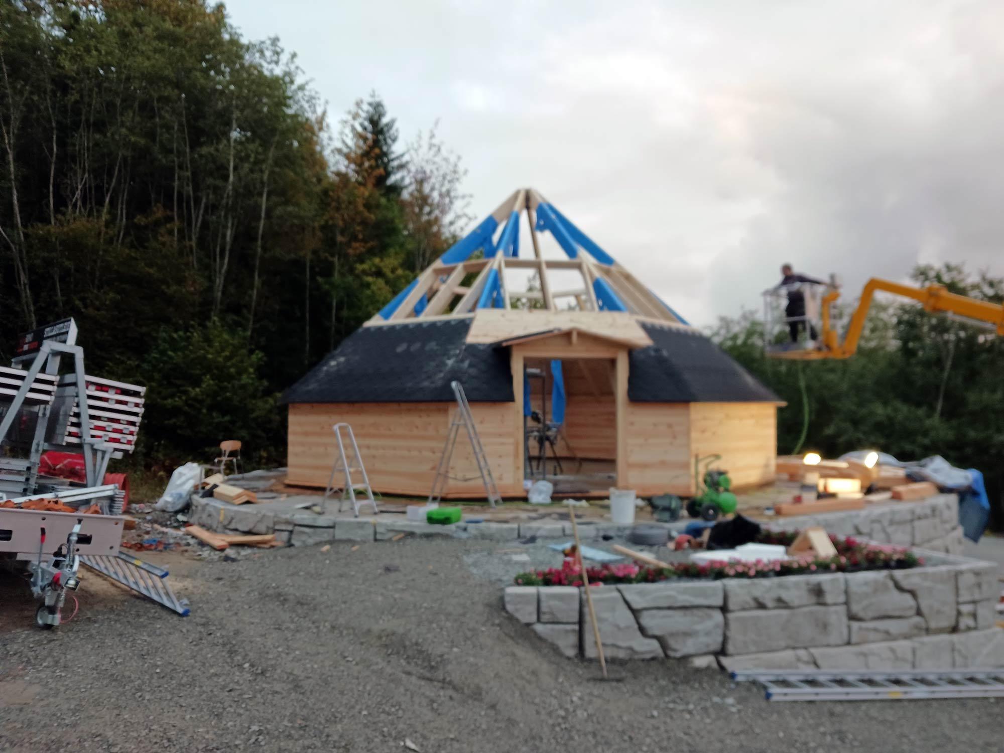 The roof frame of a round building going up, the Rømo van in front